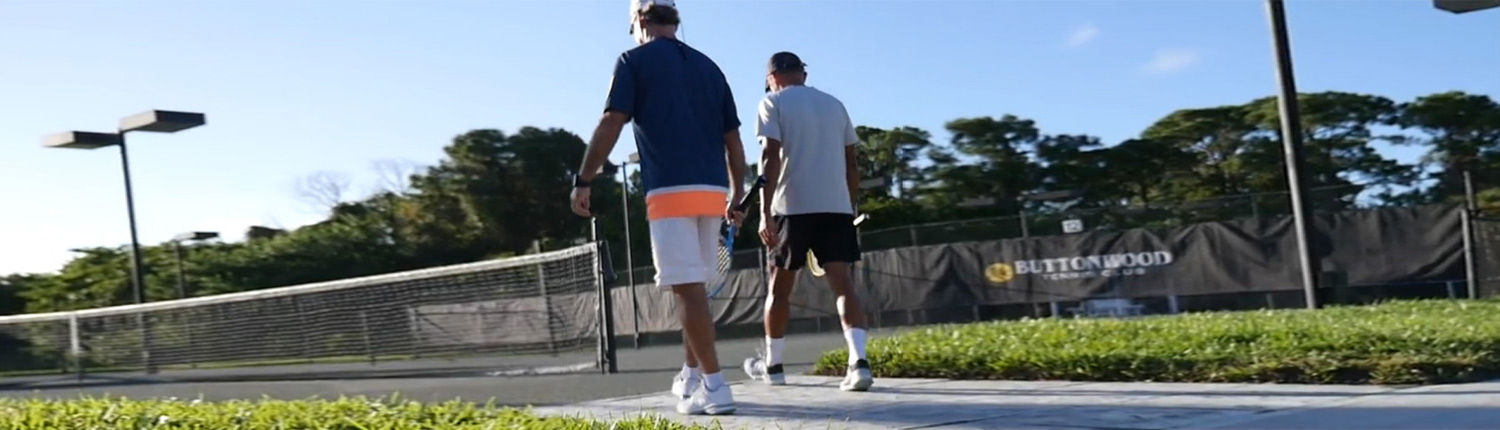 Two tennis player walking on the tennis court with their racquet